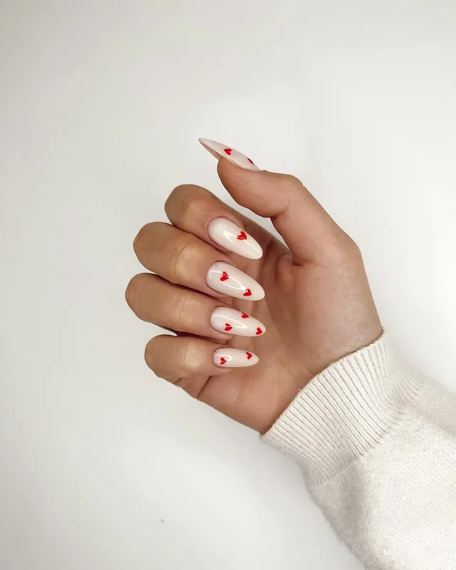 Uñas nude con pequeños corazones rojos, diseño de Manicuí