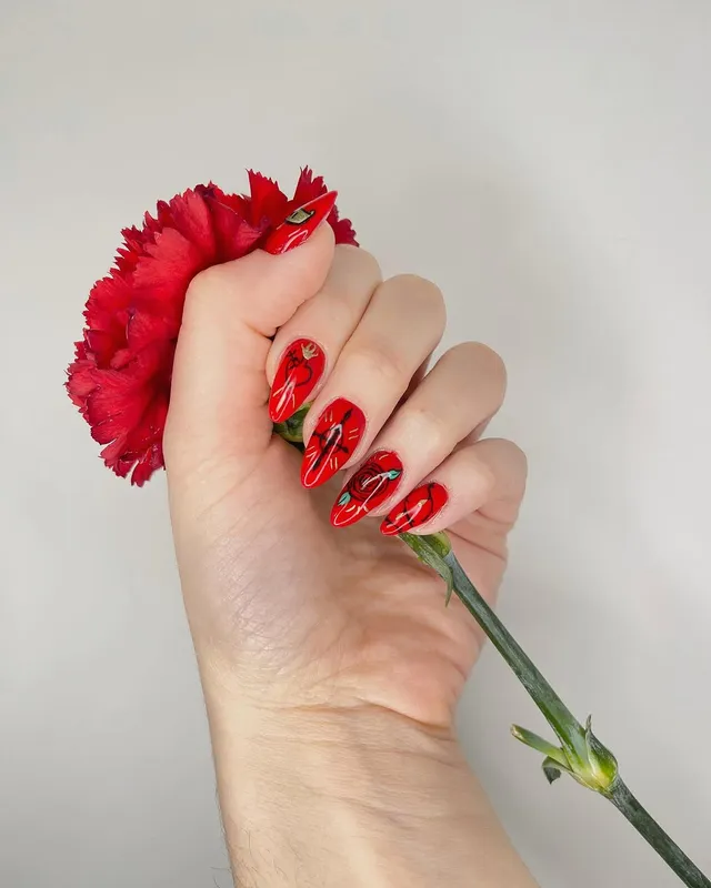Uñas rojas sujetando un clavel, diseño floral de Manicuí