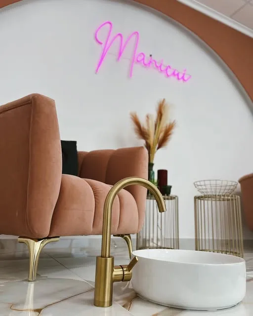 Rincón del salón Manicuí, con sillón terracota y el logo en neón